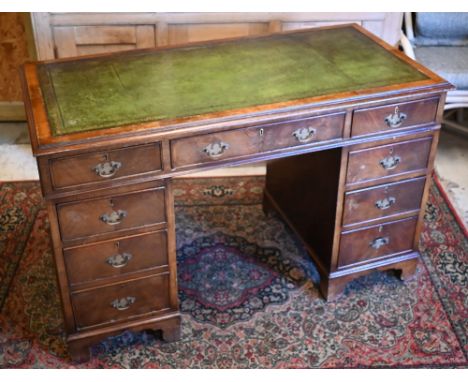 An old walnut leather top pedestal desk with an arrangement of nine drawers raised on shaped bracket feet, 122 x 62 x 77 cm h