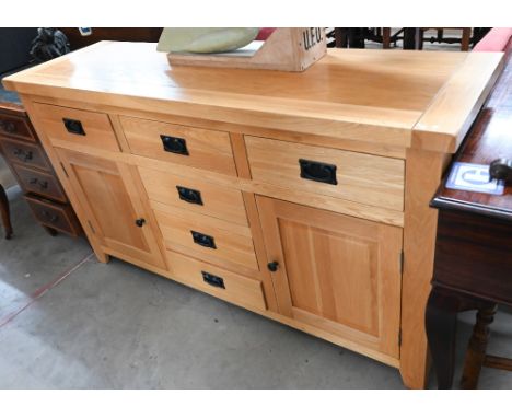 A solid light oak modern sideboard with arrangement of six drawers around panelled cupboards, 150 cm wide x 45 cm deep x 85 c