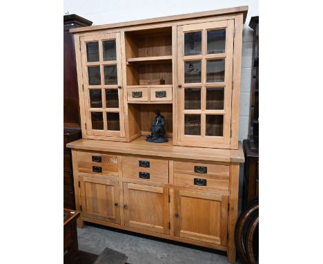 A solid light oak modern dresser, the top with glazed cupboards flanking open shelves and small drawers on base with three dr