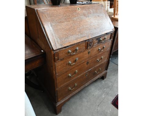 A Georgian oak fall front bureau with six drawers (the small drawer with secret compartment), raised on bracket feet, 88 cm w