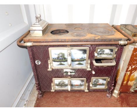 A Continental early 20thC cast iron and enamel kitchen range, the doors and sides decorated with panels of lakeside views, ra
