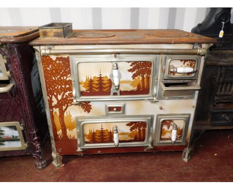 A French early 20thC cast iron and enamel kitchen range, Loussert St Etienne, the front and doors decorated with silhouetted 