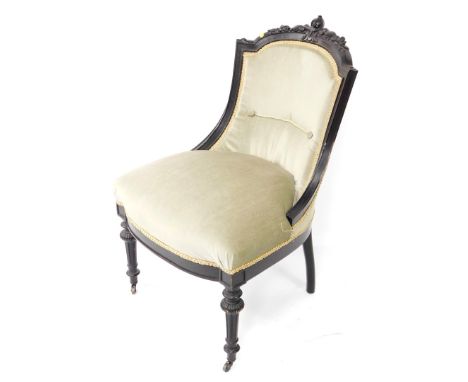 A Victorian ebonised nursing chair, with a foliate carved crest rail, green overstuffed seat and button back, raised on flute