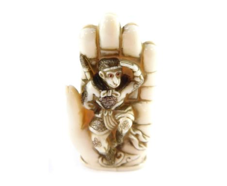 A Japanese late Taisho / early Showa  period  ivory netsuke of a hand, enclosing a figure of Sun Wukong, signed, 49mm high.