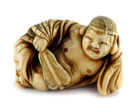 A Japanese Meiji period ivory netsuke of the reclining Buddha, unsigned, 40mm wide.