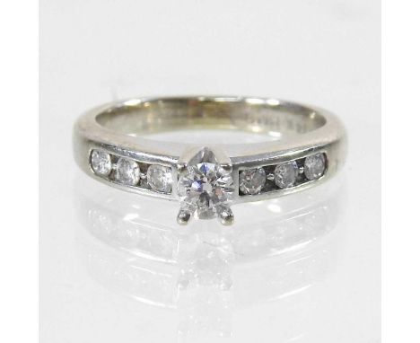A 14 carat white gold diamond ring, set with a central diamond, flanked by six diamonds to the shoulders, size J, boxed