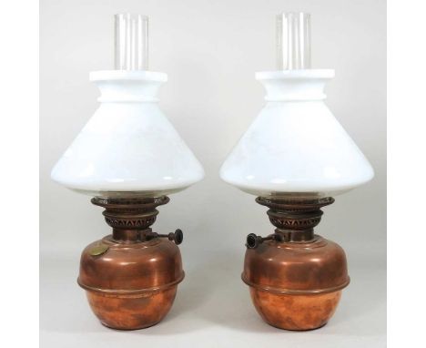 A pair of early 20th century copper oil lamp fonts, with opaque glass shades, 37cm high (2)