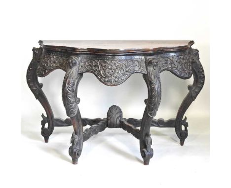 A 19th century Anglo-Indian carved hardwood console table, of serpentine shape, on a heavily carved base decorated with masks