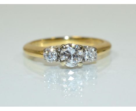 A diamond three stone ring, a round brilliant cut diamond spaced by two smaller diamonds in claw settings, to tapered shoulde