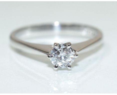 An 18 carat white gold solitaire diamond ring, a round brilliant cut diamond in a claw setting, to knife edge shoulders, esti