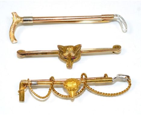 A fox and crop brooch, a fox head to a crop bar, measures 5cm, stamped '15CT'; a fox head bar brooch, with ruby set eyes, sta