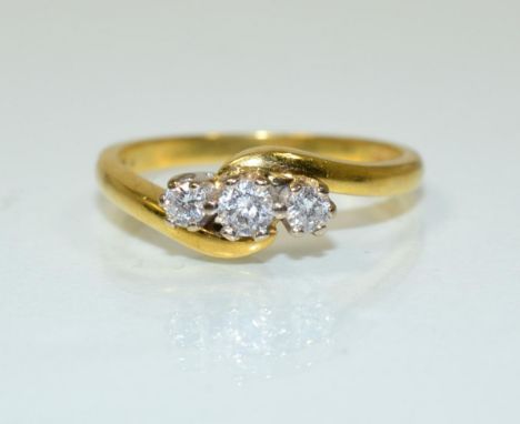 An 18 carat gold diamond three stone ring, a round brilliant cut diamond spaced by two smaller diamonds in claw settings, to 