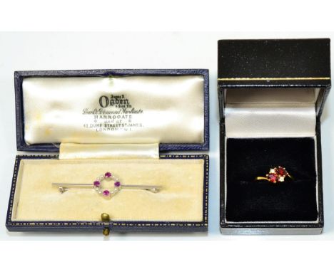 A 9 carat white gold ruby and seed pearl brooch, a hoop of four round cut rubies in milgrain settings, spaced by pairs of see