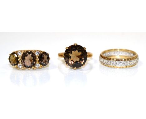 A 9 carat gold smokey quartz and cubic zirconia ring, three graduated smokey quartz spaced by pairs of cubic zirconia, in a c