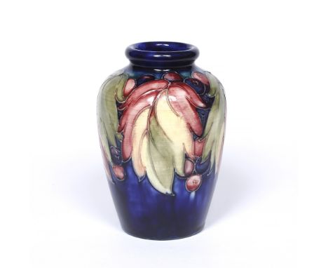 William Moorcroft (1872-1945) 'Leaf and Grape' pattern vase, circa 1930s decorated with coloured fruit and leaves on dark blu