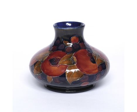 William Moorcroft (1872-1945) 'Pomegranate' pattern squat vase, circa 1920 decorated with coloured fruit and leaves on blue g