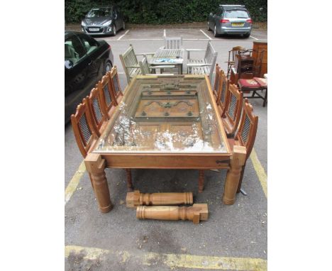 A 19th century and later Asian teak dining table constructed from a carved door and frame with brass studs and a door knocker