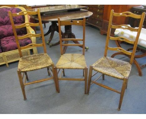 Three early 20th century ladder back occasional chairs with rush seats 