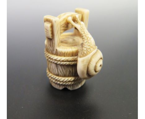 A Japanese Ivory Netsuke carved in the form of a snail climbing a bucket, signed to the base, c. 40mm