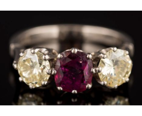 A ruby and yellow diamond three-stone ring: with central cushion-shaped ruby approximately 1.0ct claw-set between pale yellow