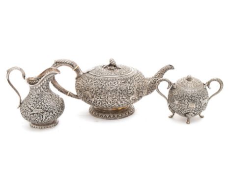 A matched  Indian silver three-piece tea service.: the teapot of squat globular form decorated with animals within low relief