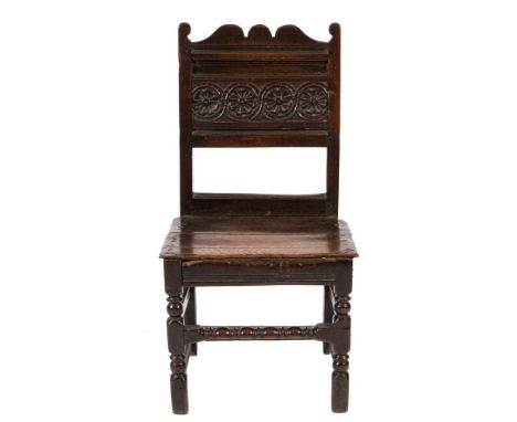 A late 17th/early 18th Century oak side chair:, the moulded panel back with guilloche roundel and carved flowerhead ornament 