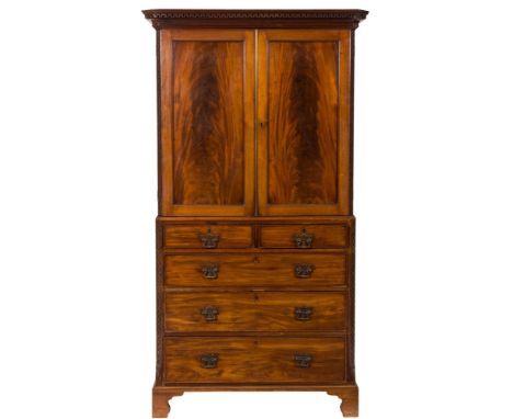 A 19th Century mahogany linen press:, the upper part with a moulded dentil cornice and blind fret carved canted angles, fitte