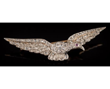 A rose diamond mounted eagle in flight brooch: pave-set throughout with rose diamonds and single cabochon ruby eye, 50mm tota