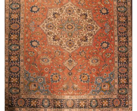 A Tabriz carpet:, the shaded brick red field with a central geometric flowerhead pole medallion and all over palmette designs