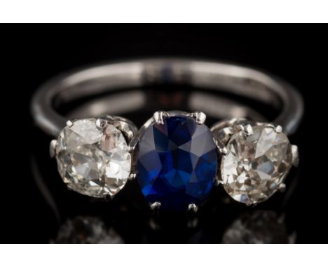 A sapphire and diamond three-stone ring: with central oval sapphire between round old brilliant-cut diamonds estimated to wei