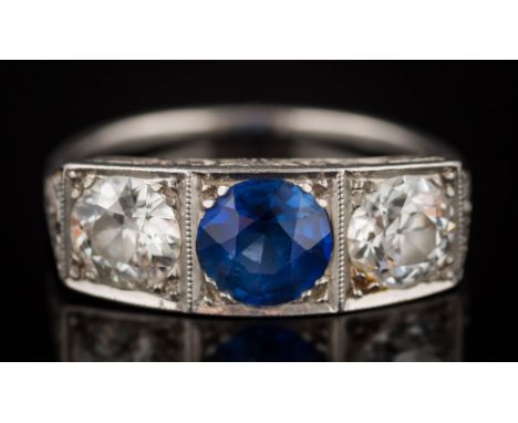 A platinum, synthetic sapphire and diamond three-stone ring:with central round synthetic sapphire 6.4mm diameter between roun