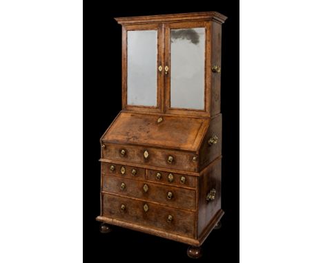 A William and Mary walnut veneer and feather banded bureau cabinet:, in three sections, the upper part with a moulded cornice