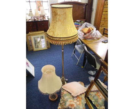 A brass standard lamp with shade, a table lamp with shade and three cushions.