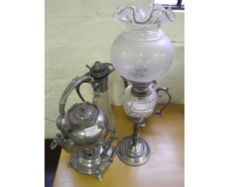 A plated kettle on stand, plated teapot, an oil lamp and a claret jug.