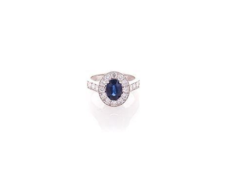 A SAPPHIRE AND DIAMOND RING claw-set to the centre with an oval mixed-cut sapphire weighing approximately 1.56cts, the confor