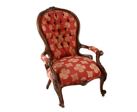 A VICTORIAN WALNUT GRANDFATHER CHAIR the curved button-back within a conforming frame centred by a foliate carving, padded ar