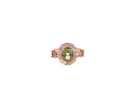 A TOURMALINE AND DIAMOND RING centred with an oval mixed-cut green tourmaline weighing approximately 2.03cts, within a confor