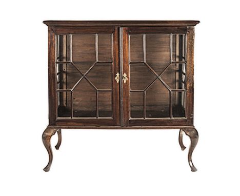 A CAPE STINKWOOD DISPLAY CABINET, 19TH CENTURY the rectangular plain top above a pair of glazed paneled doors enclosing a com