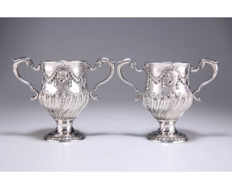 A PAIR OF GEORGE III IRISH SILVER TWO-HANDLED CUPS by Matthew West, Dublin, c.1775, each chased with a portrait medallion, fo