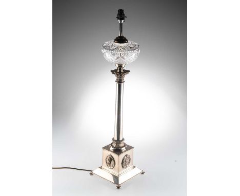 A VICTORIAN SILVER-PLATED TABLE LAMP with cut-glass reservoir, the square plinth with a portrait medallion to each side, rais