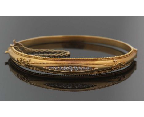 A late Victorian Etruscan style 15ct diamond bangle, the upper half of the hinged bangle set with graduated single cut diamon