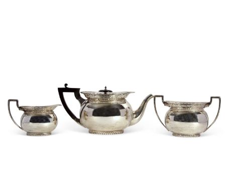 A George V silver tea set of compressed oval form having pierced scroll decorated rims and applied gadrooned edges, plain bod