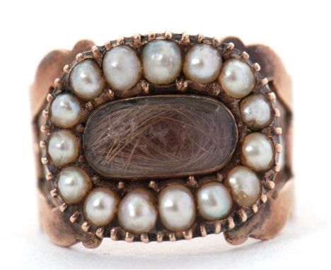 An early 19th century seed pearl and hairwork mourning ring, the central oval hairwork panel, surrounded by split pearls, wit