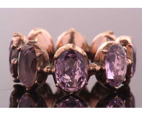 A 19th century foil backed amethyst eternity ring, the oval foil backed amethysts in closed backs of unmarked yellow-rose met