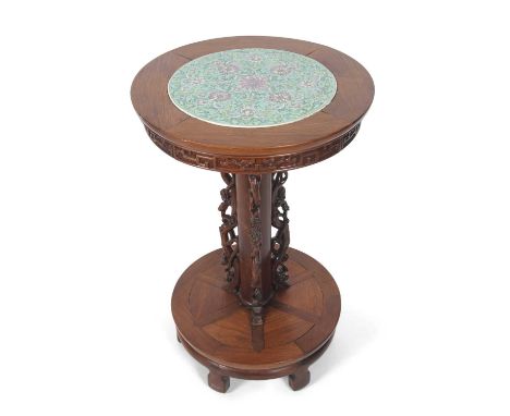 A Chinese hardwood lamp table with a circular top inset with a Chinese porcelain charger with a famille rose floral design on