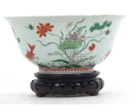 A Chinese famille vert porcelain bowl, Kangxi, with everted rim decorated with flowering plants and weeds with goldfish in an