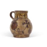 An early 18th Century pottery mug, possibly Devon slip ware decorated with tulips and dated 1743,
