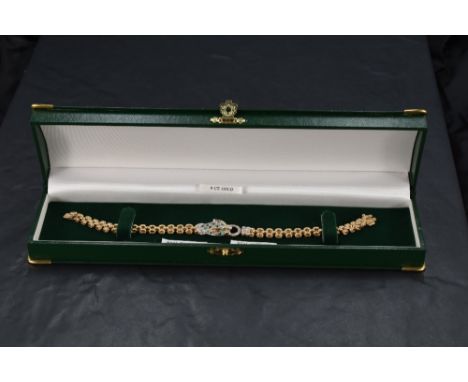 A 9ct gold bracelet having a central panther head panel with emerald and diamond chip decoration, on a brick effect bracelet 