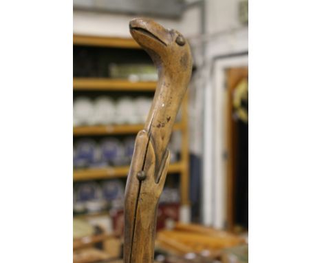 A folk art walking stick modelled as a snake eating a bird