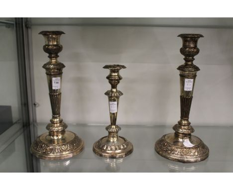 A pair of plated candlesticks and similar smaller candlestick
